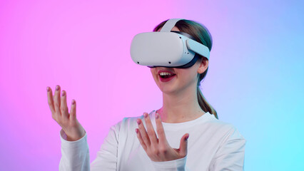 Poster - Young woman in white clothes and vr goggles gesture hands isolated over neon background