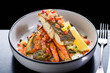A serving of crispy skin grilled barramundi fish with roast vegetables in a round white bowl