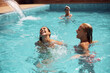Happy women laugh and have fun while spending summer day in swimming pool.