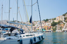 White Yacht Arriving To Colorful Symi Harbour On A Sunny Day. Greece.