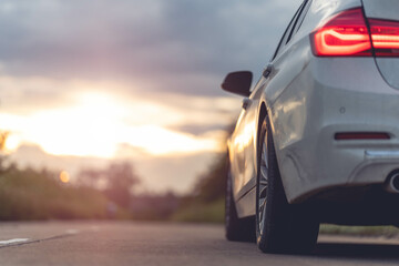 Wall Mural - Behind a beautiful white car parked on a road with beautiful sunsets. with space for text.