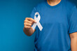 © meeboonstudio - A female hand is holding a white ribbon on a blue background