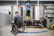Person With Disability Who Uses A Wheelchair Working At Craft Beer Factory. High Quality Photography.