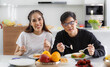 © atitaph - young Asian couple Happy to sit and eat at the dining table in the kitchen at home