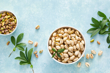 Wall Mural - Pistachios. Whole pistachios with green leaves and pistachio nut kernels. Healthy natural vegetarian organic food. Top view, copy space