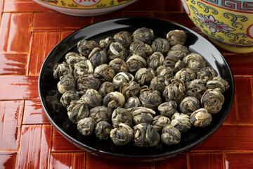 Wall Mural - Dried Chinese Jasmine Dragon pearl tea leaves on a black bowl