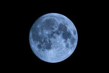blue full moon on dark black sky background, shot from surface of earth with very long telephoto len