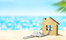 House By The Sea Concept. Figure Of House And Key On Sandy Beach