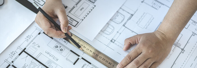 Engineer and Architect concept, Man uses a ruler to measure the floor plan on the blueprint, Building architecture design work, Construction design project under environmental conservation conditions.