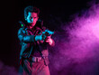 © Ulia Koltyrina - A guy in a cyberpunk image, aiming a gun at someone. a futuristic character. A young man in neon lighting on a black background