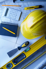 Contractor theme. Plans,  notebook and tool kit of the contractor: yellow hardhat, libella and yardstick. 