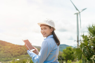 Female engineer working on the seaside wearing a protective helmet over electrical turbines background..