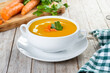 Carrot soup with cream and parsley on rustic wooden table