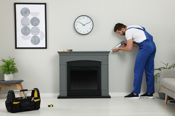 Sticker - Professional technician sealing electric fireplace with caulk near white wall in room