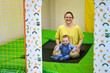 Happy toddler baby boy jumps on a trampoline with his mother in the playroom. Kid age one year