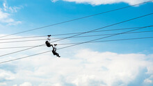 Zipline Riders, Silhouettes Of Two People On Blue Sky Background