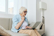 © Tatiana - an elderly lady looks at a laptop monitor showing her fist while talking via video link while at home