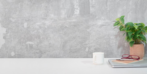 Wall Mural - Comfortable workplace with laptop, stationery, picture frame and potted plant on white table.