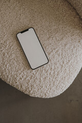 Blank screen mobile phone with copy space on chair. Flat lay, top view. Copy space mockup template.