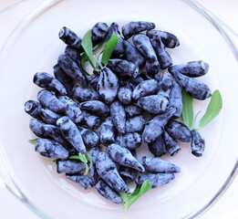 Canvas Print - Ripe and juicy honeysuckle berries on glass plate. Glass bowl with honeysuckle berry