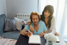 Smiling Woman With Grandmother Using Tablet PC At Home