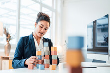 Businesswoman With Toy Blocks Sitting At Desk In Office