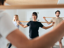 Dedicated Man And Women Practicing Stick Yoga In Fitness Studio