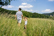 © Westend61 - Father and daughter walking through field on sunny day