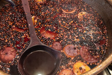 Bowl Of Traditional English Hot Spicy Mulled Wine With Cloves, Cinnamon Sticks, Dried Fruit And Red Wine On Sale At Bath Christmas Market.