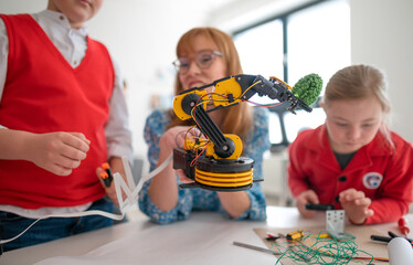 Wall Mural - group of kids with young science teacher programming electric toys and robots at robotics classroom