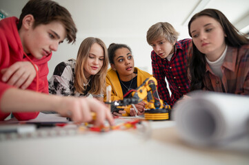 group of students building and programming electric toys and robots at robotics classroom