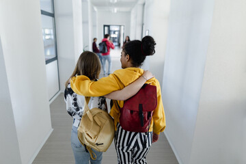 Wall Mural - Rear view of young high school students walking in corridor at school, back to school concept.