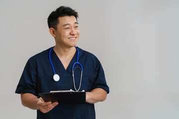 Wall Mural - Adult man wearing medical uniform and stethoscope holding clipboard