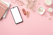 Business concept. Top view photo of workplace smartphone candles diaries pencils stylish glasses gold rings trendy barrettes and white gypsophila flowers on isolated pastel pink background