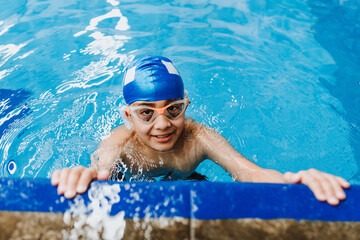 Wall Mural - latin child boy swimmer wearing cap and goggles in a swimming training at the Pool in Mexico Latin America	