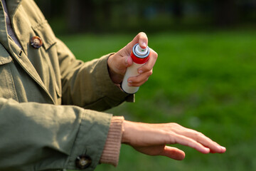 Wall Mural - health care, protection and people concept - woman spraying insect repellent or bug spray to her hand at park