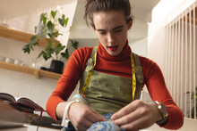 Image Of Caucasian Non-binary Trans Woman With Fabric Working In Sewing Workshop