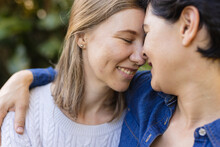 Close-up Of Romantic Caucasian Lesbian Couple With Eyes Closed And Face To Face Romancing In Yard
