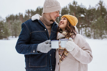 Sticker - people, season, love, drinks and leisure concept - happy couple with tea cups in snowy winter park