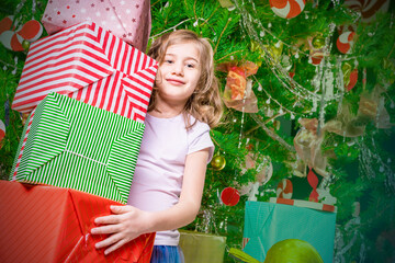 Joyful girl with a large stack of gift boxes stands