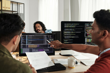 Wall Mural - team of indian software developers discussing programming code on computer screen