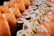 Close up of maki sushi sprinkled with sesame lying among other types of rolls.
