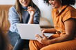 © (JLco) Julia Amaral - Cheerful businesswomen using a laptop together in an office lobby