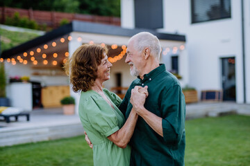 Senior woman nad man dancing together in a garden in summer