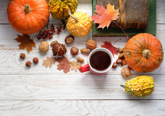 Wall Mural - tea cup, pumpkins, nuts, books and autumn leaves on white wooden table background. autumn season, home cozy composition. fall time concept. flat lay