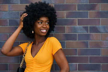 Wall Mural - Portrait of young black woman with afro hairstyle smiling in urban background