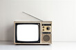 Retro old television with cut out screen on white table in front of gray wall background, front view, blank screen