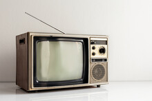 Vintage Old Television On White Table With Antenna In Front Of White Wall Background.