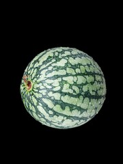 Wall Mural - Vertical shot of a small green watermelon isolated on a black background