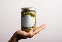 Closeup Of Pickled Okra Conserve With A Round Cap Inside Hand